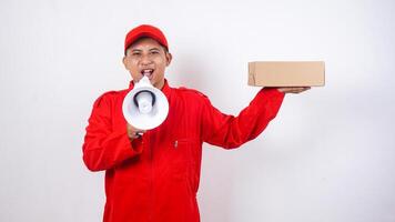 Asian Delivery man in red uniform with a package box parcel and megaphone isolated on white background photo