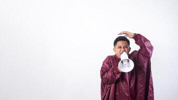 Asian man in red raincoat holds megaphone and covering his head with hand to shield face from rain isolated on white background photo