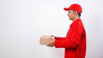 Side view of Asian Delivery man in red uniform holding a package box parcel isolated on white background photo