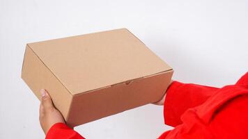 Close up of delivery man in red uniform holds a package box parcel isolated on white background photo