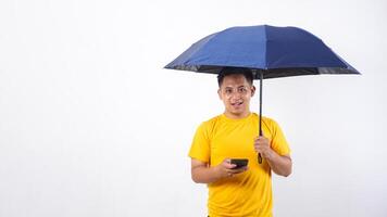 Handsome Asian man holds umbrella and smartphone isolated on white background photo