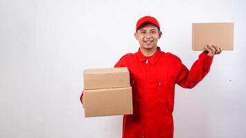 Delivery man in red uniform carrying package boxes and showing other package box to customer to camera isolated on white background photo