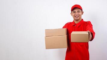 Delivery man in red uniform carrying package boxes and giving other package box to customer isolated on white background photo
