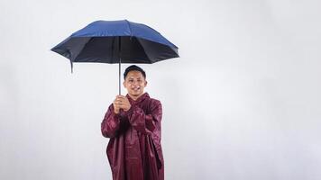 Smiling Asian man in red raincoat holds umbrella isolated on white background photo