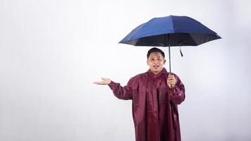 Asian man in red raincoat holds umbrella raising his arm isolated on white background photo