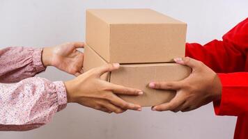 Close up of Delivery man in red uniform holding package boxes parcel to customer isolated on white background photo