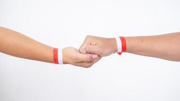Two men hands with red and white wristband gripping each in firm handshake other isolated on white background photo