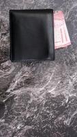Yogyakarta, Indonesia, 2025 - Wallet with several Indonesian Rupiah banknotes in it isolated on pattern background photo