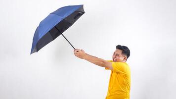 Asian man holding an umbrella tightly because of the strong wind isolated on white background photo