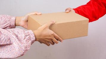 Close up of customer taking a package box parcel delivered by delivery man in red uniform isolated on white background photo