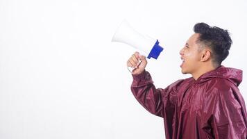 Side view of Asian man in red raincoat shouting on megaphone isolated on white background photo