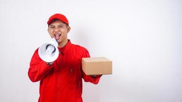 Asian Delivery man in red uniform with a package box parcel and shout using megaphone isolated on white background photo