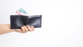 Yogyakarta, Indonesia, 2025 - Hand holding wallet with several Indonesian Rupiah banknotes with different values in it isolated on white background photo