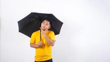 Asian man holding umbrella and look up to the sky to checking if rain stopped isolated on white background photo