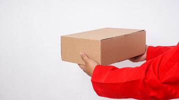 Close up of delivery man in red uniform deliver a package box parcel to customer isolated on white background photo