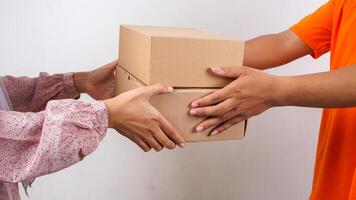 Close up of customer taking package boxes parcel given by delivery man in orange t-shirt isolated on white background photo