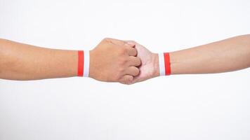 Close up of two men hands with red and white wristband gripping each other isolated on white background photo