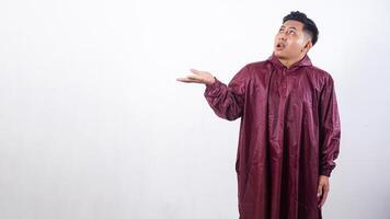 Asian man in red raincoat checking if rain stopped while looking up to the sky isolated on white background photo