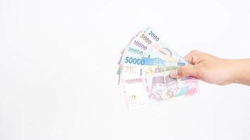 Yogyakarta, Indonesia, 2025 - Hand holds several Indonesian Rupiah banknotes with different values isolated on white background photo