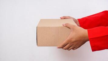 Close up of delivery man in red uniform holding a package box parcel to deliver to customer isolated on white background photo