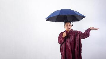 Portrait of Asian man in red raincoat holds umbrella raising his arm to presenting empty space for copy space advertisement isolated on white background photo