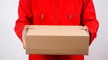Close up of delivery man in red uniform holding a package box parcel isolated on white background photo