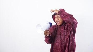 Asian man in red raincoat shout using megaphone while covering his head with hand to shield from rain isolated on white background photo