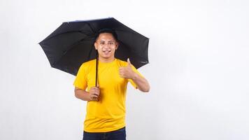Asian man holds an umbrella and showing his thumb up isolated on white background photo