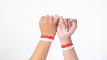 Close up of two men hands with red and white wristband doing pinky promise sign isolated on white background photo