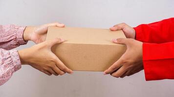 Close up of customer taking a package box given by delivery man in red uniform isolated on white background photo