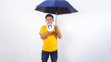 Asian man holds an umbrella and shout using megaphone isolated on white background photo