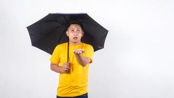 Asian man holding umbrella and checking if rain stopped isolated on white background photo