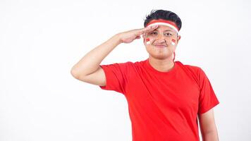 Indonesian man celebrate Indonesia independence day on August 17 by using red and white attribute and giving salute to camera isolated on white background photo