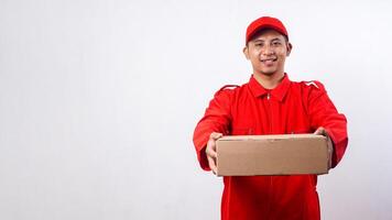 Delivery man in red uniform giving cardboard parcel box isolated on white background photo