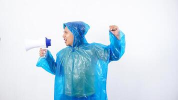 Side view of Asian young man in blue raincoat shout using megaphone isolated on white background photo