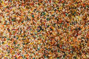 Vivid surface full of mixed gems, pearls, and beads. Decorative stones in rich hues create a shiny and artistic natural background photo