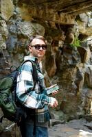 Russian tourist man in sunglasses with backpack using phone map to find way in Yuyuan Garden, Shanghai, China. Exploring rocky scenic path photo