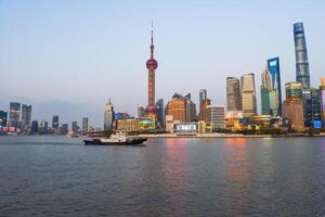 Shanghai, China - 1 April 2025 Tourist boat passes along the Bund waterfront in front of Pudong skyline featuring Oriental Pearl Tower and Shanghai Tower photo