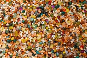 Colorful background of assorted polished gemstones, pearls, and crystals. Bright, vibrant texture of mixed natural stones and beads in various shapes and colors, ideal for abstract backdrop photo