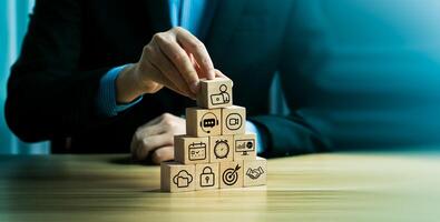 Business Strategy and Remote Work Integration Concept, Hand Building Wooden Pyramid with Technology Icons Representing Online Collaboration, Security, Cloud Service, Planning, Digital Transformation photo