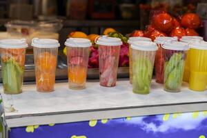 Colorful plastic cups filled with fresh fruits for juice or smoothies at a street food stall in Shanghai, China photo