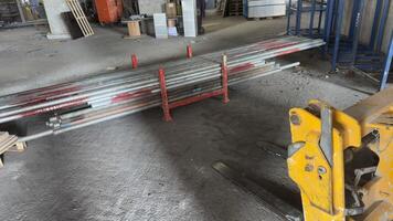 Stacked Metal Pipes in Red Rack with Forklift in Warehouse photo