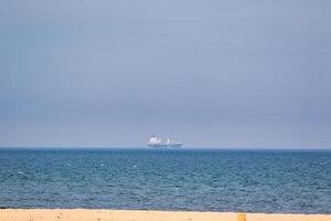 Cargo Ship on Ocean Horizon from Beach at Sandhaven Beach, UK photo