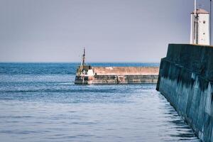 Concrete Pier Walls and Lighthouse in a Seascape at Seahouses Harbour, UK photo