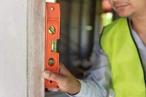 Contactor is inspecting construction and quality assurance new house using a level. Engineers or architects or contactor work to build the house before handing it over to the homeowner photo