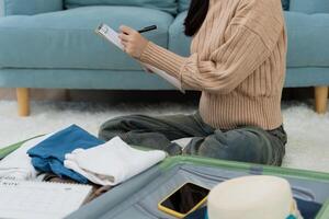 Travel bag. female are checking the detail and quantity of items used during the trip by checklist. Young women are prepare clothes and personal belongings. photo