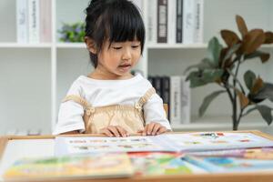 Happy Asian children relax read book at home. daughter and reading a story. learn development, childcare, laughing, education, storytelling, practice, imagine, reduce addiction mobile photo