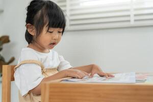 Happy Asian child relax read book at home. daughter and reading a story. learn development, childcare, laughing, education, storytelling, practice, imagine, reduce addiction mobile phone photo