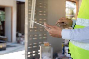 inspector or engineer is inspect construction and quality assurance new house using a tablet. Engineers or architects or contactor work to build the house before handing it over to the homeowner photo