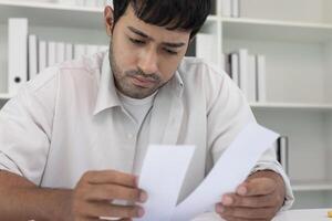 Stressed asian man with large bills or invoices no money to pay to expenses and credit card debt. shortage, Financial problems, mortgage, loan, bankruptcy, bankrupt, poor, empty wallet photo
